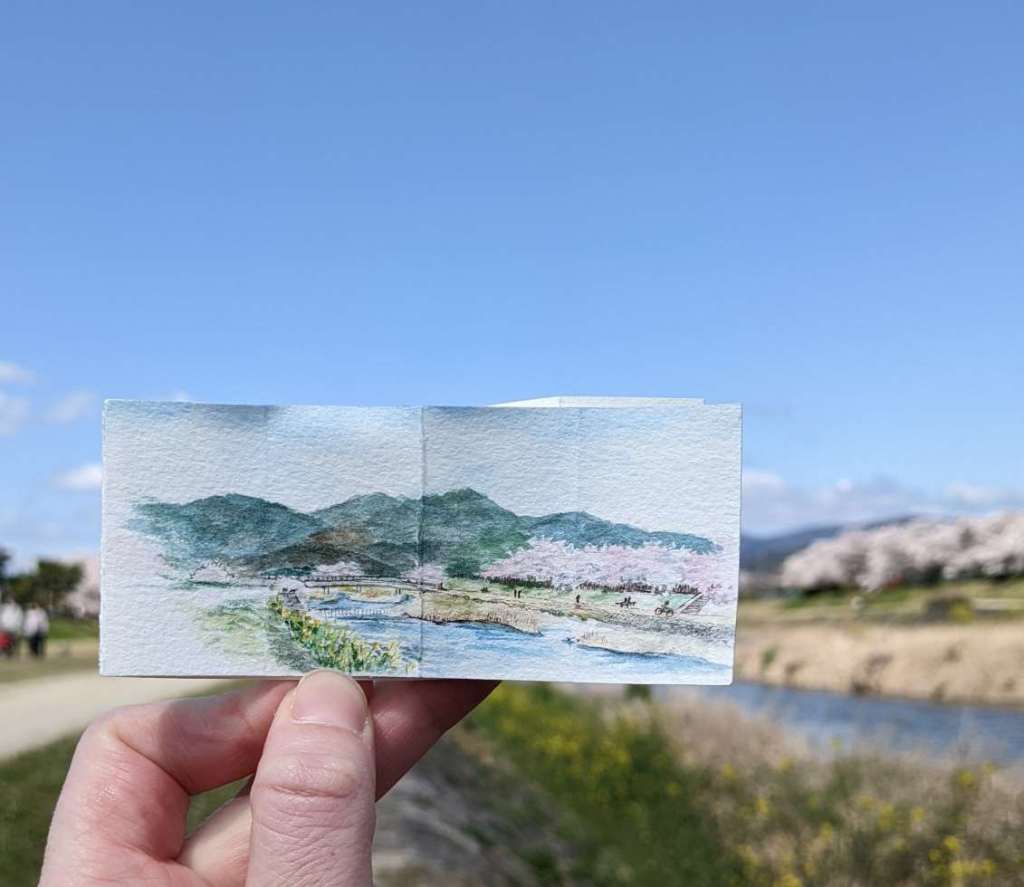 a miniature painting of a riverbank lined with blooming sakura